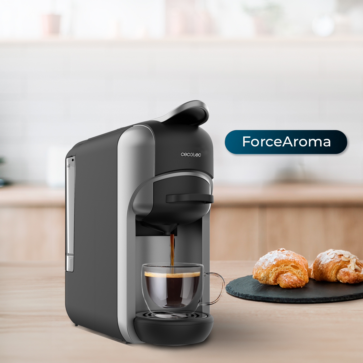 Una cafetera vierte café en una taza de cristal transparente. Dos cruasanes en un plato negro. La máquina tiene una etiqueta 'ForceAroma'.