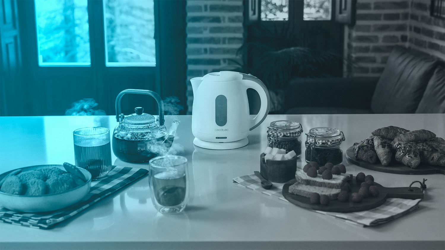 Una mesa con té, una tetera, pasteles y fruta. Una tetera de vidrio transparente humea. Dos vasos de té están en la mesa.