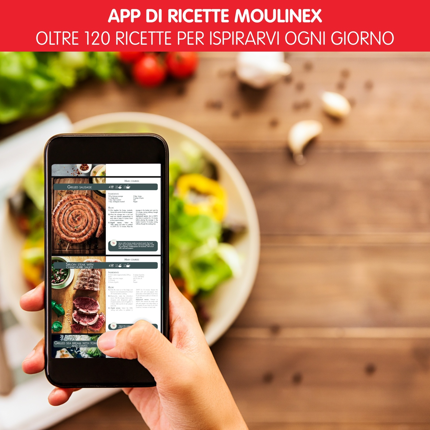 Una mano tiene un telefono che mostra un'app di ricette. Su un tavolo di legno, un piatto con insalata, aglio e pomodori è visibile sullo sfondo.