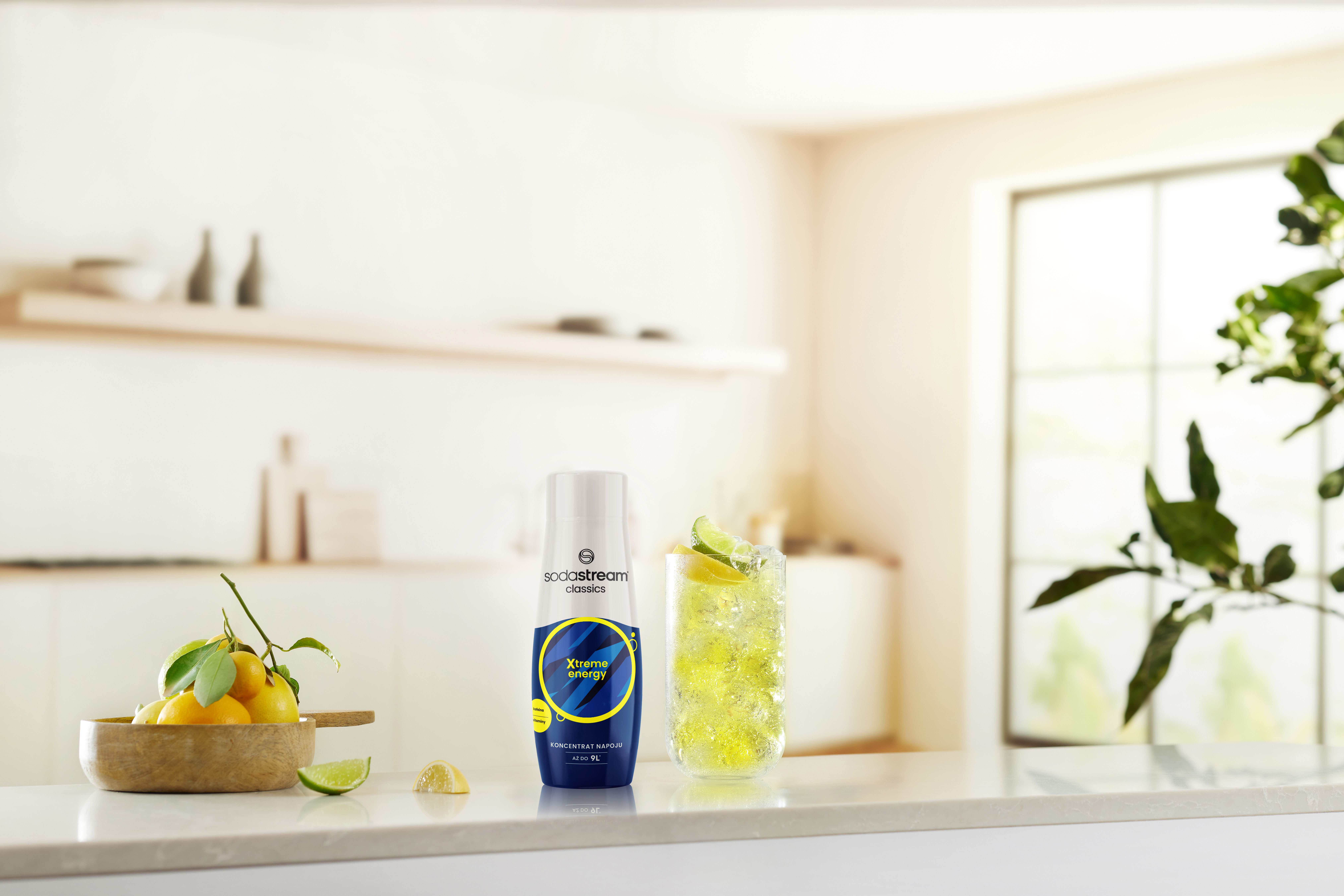 Butelka SodaStream, szklanka napoju z limonki i cytryny na blacie. Jasna, słoneczna scena kuchenna.