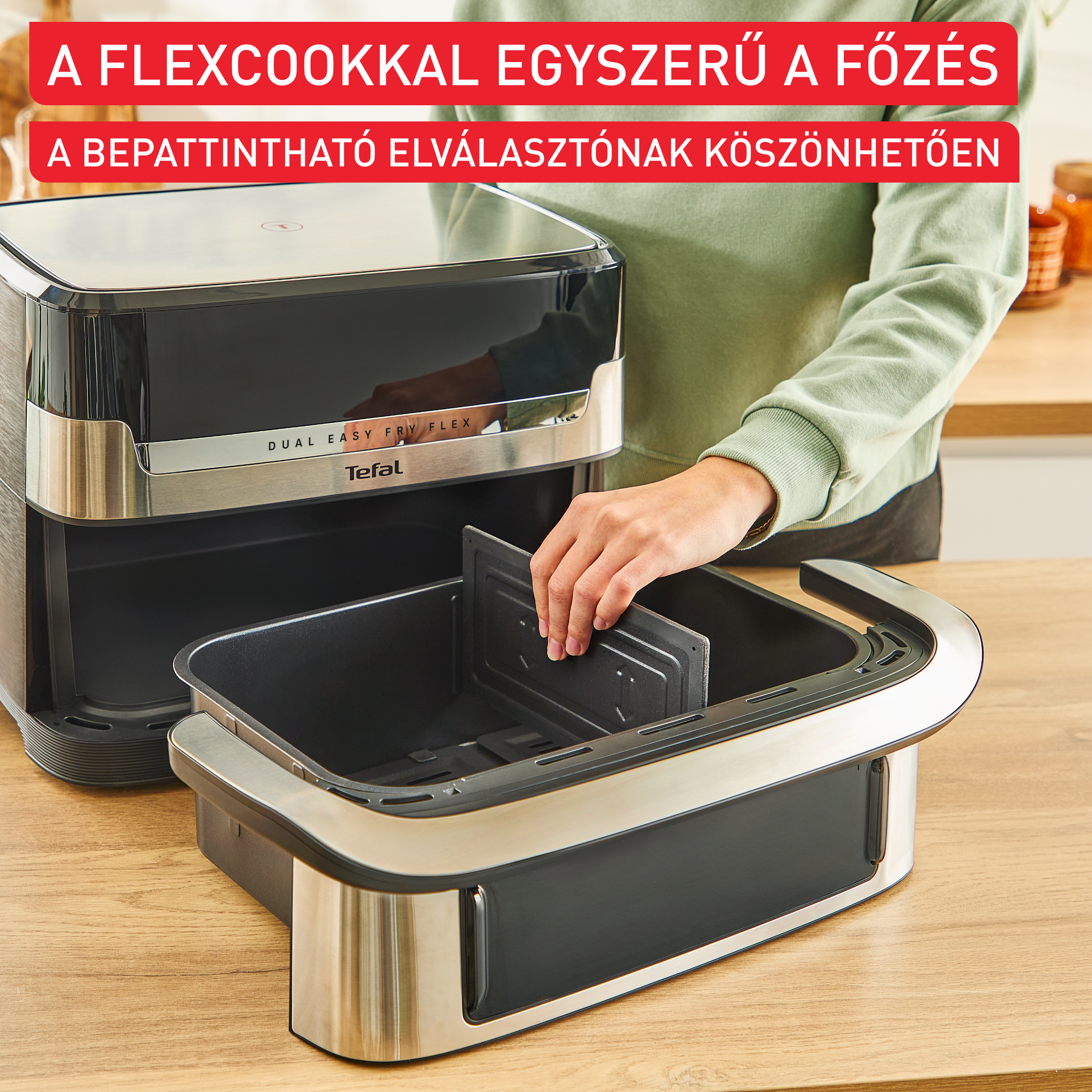 Egy személy egy elválasztót helyez a Tefal Flexcook air fryerbe. A piros szöveg azt írja: 'Könnyű főzés Flexcookkal'.