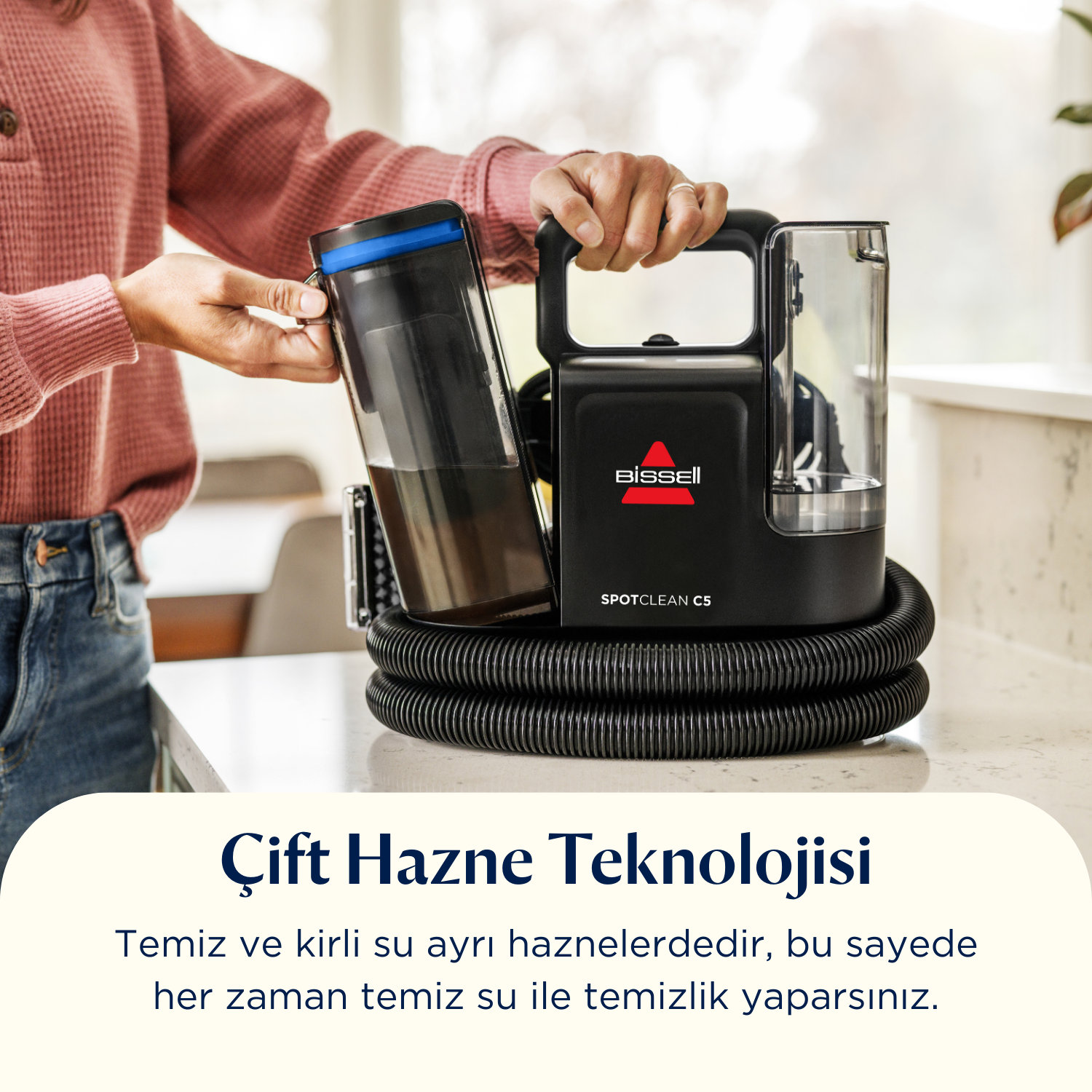 Bir kişi, su tankını göstererek, siyah ve mavi bir Bissell SpotClean C5 temizleyici tutuyor. Metin şöyle diyor: Çift Tank Teknolojisi.