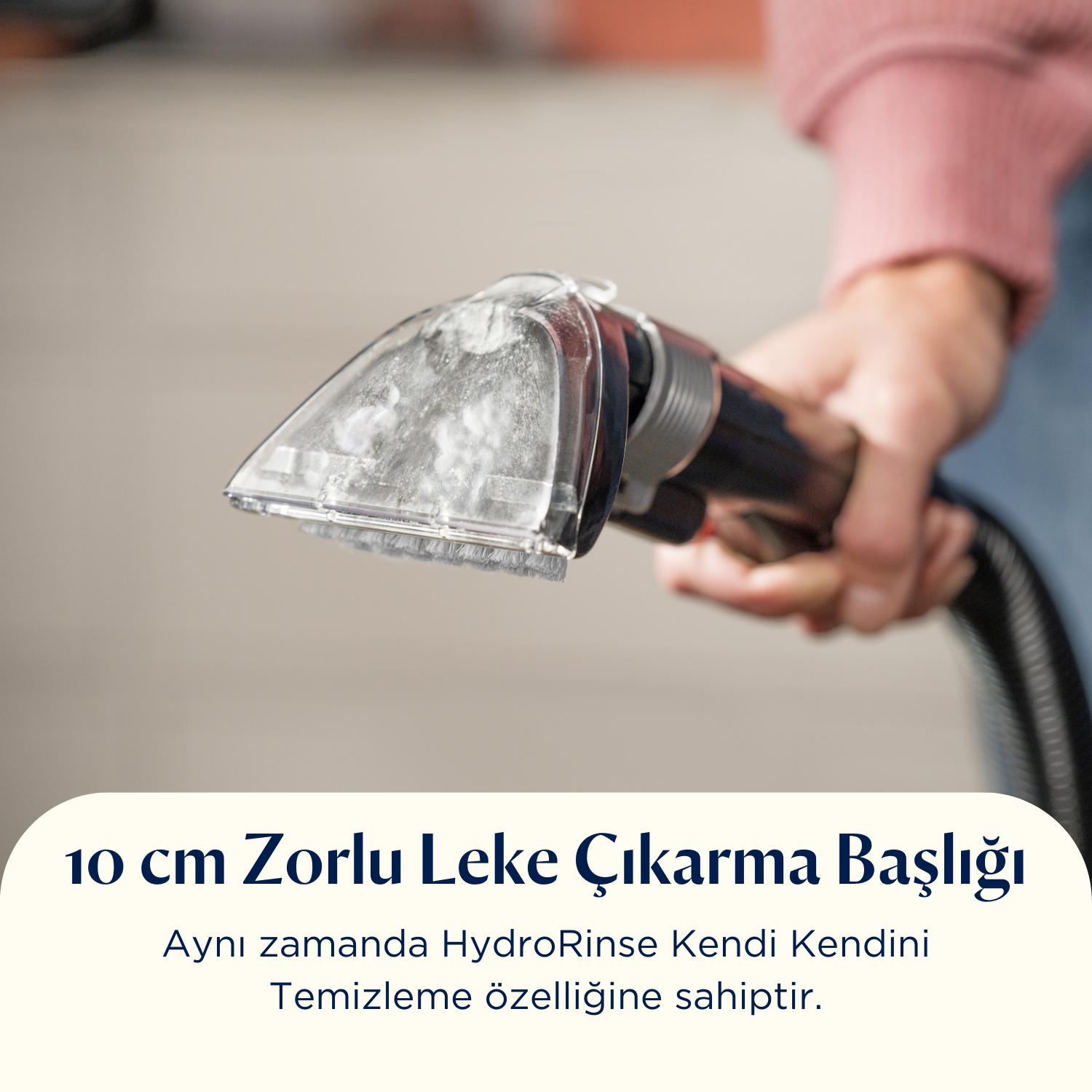 Bir kişi şeffaf bir temizleme başlığı tutuyor. Başlık pembe bir kazak yakındadır. Metin: 10 cm Leke Çıkarma Başlığı.