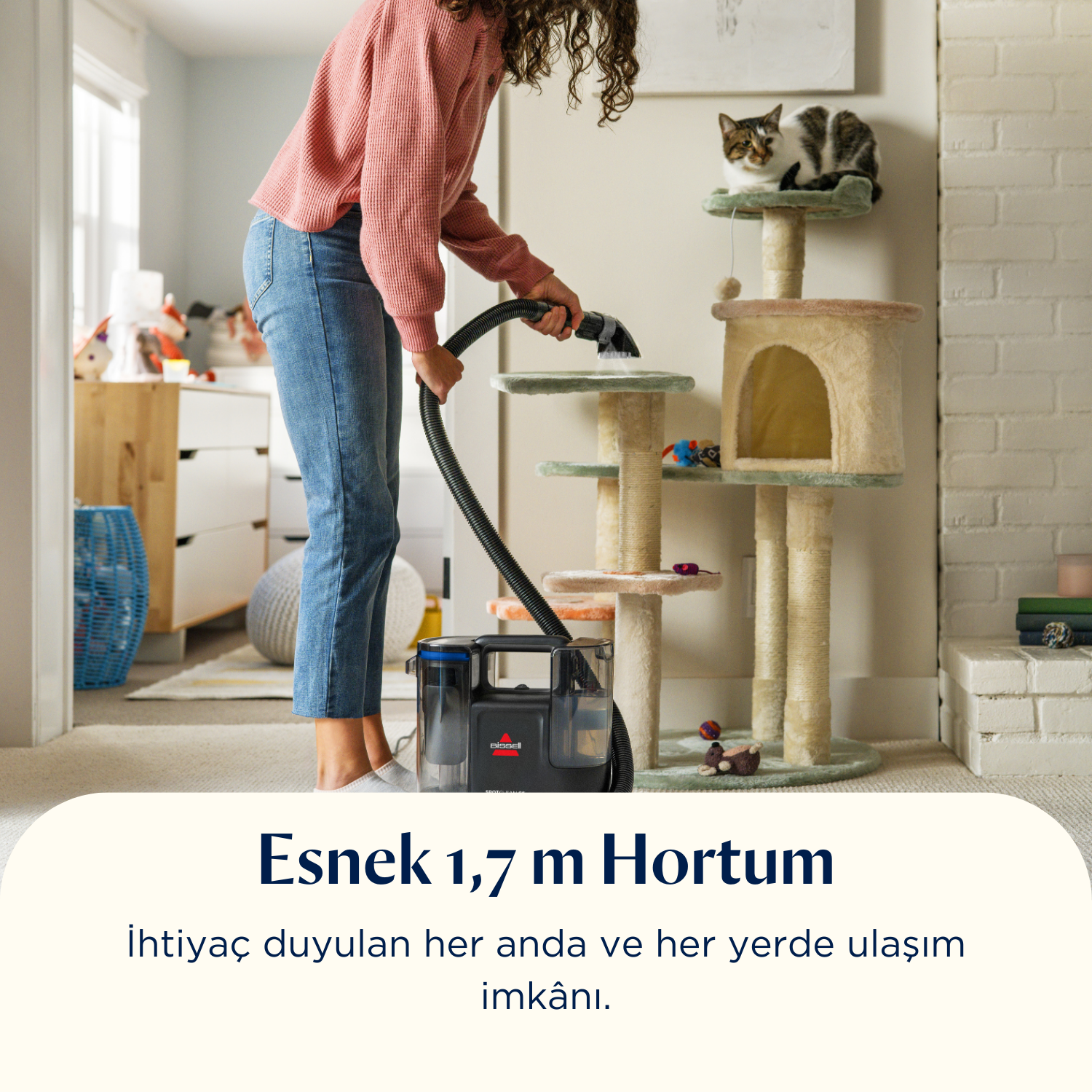 Bir kadın, Bissell temizleyiciyle halıyı süpürüyor. Arka planda iki kedili bir kedi ağacı var. Metinde 'Esnek 1,7 m Hortum' yazıyor.