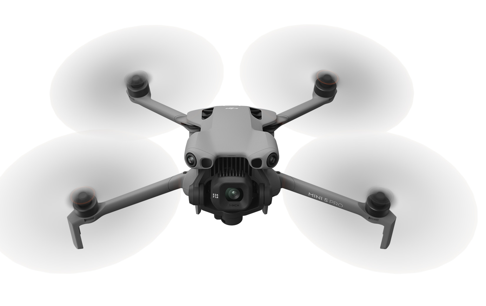 Szary dron z wirującymi śmigłami. Dron ma kamerę i jest oznaczony jako 'MINI 3 PRO'.