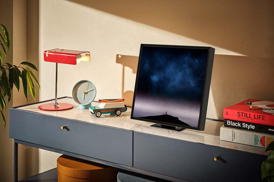 Moderne Einrichtung mit Fernseher, Lampe, Uhr und Büchern auf einem Tisch mit Marmorplatte.
