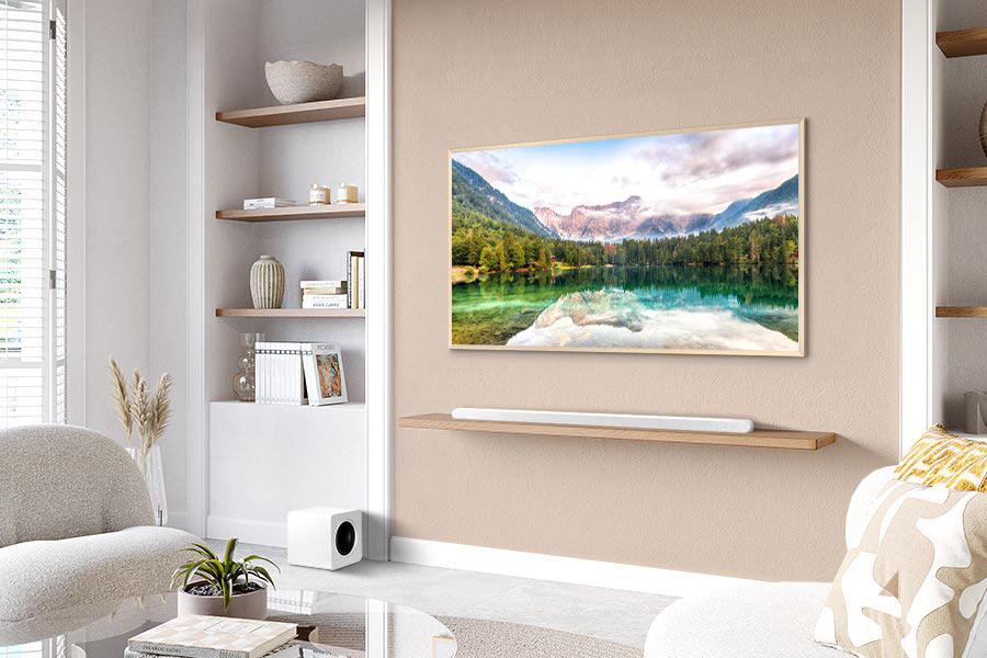 Wohnzimmer mit TV-Gerät, das eine Seeszene zeigt, einer Soundbar, Regalen mit Dekoration und einem weißen Sofa.