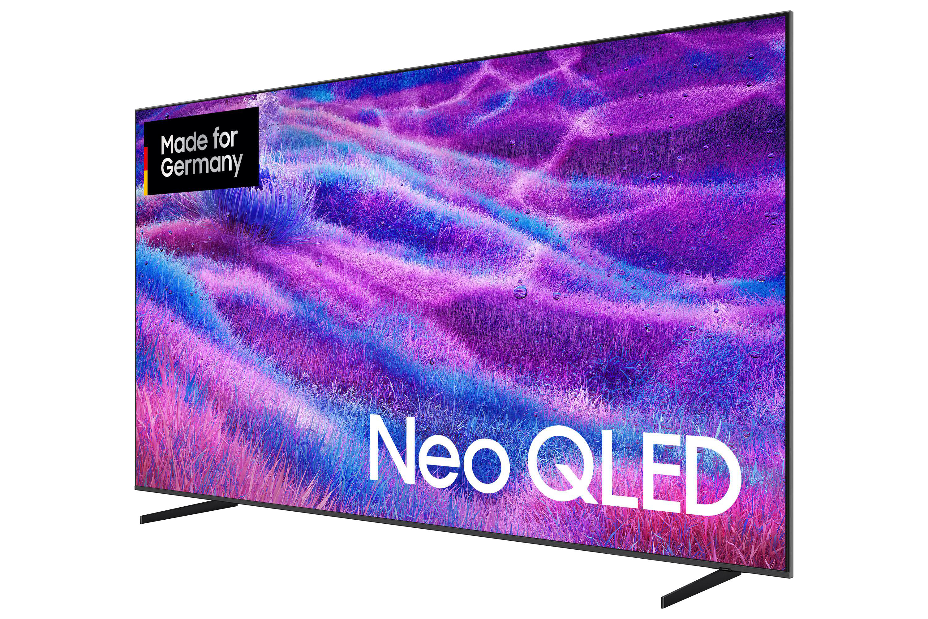 Ein Neo-QLED-Fernseher zeigt ein lila-blaues abstraktes Design. Es hat einen schwarzen Rahmen und einen Ständer, mit Text "Made for Germany".