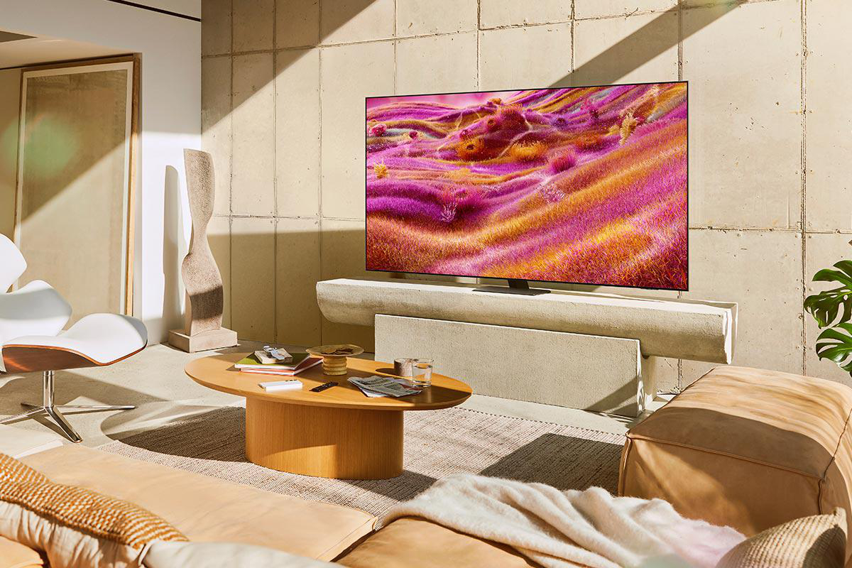 Modernes Wohnzimmer mit großem Fernseher, der farbenfrohe abstrakte Kunst zeigt, einem Holztisch und beigem Sofa.