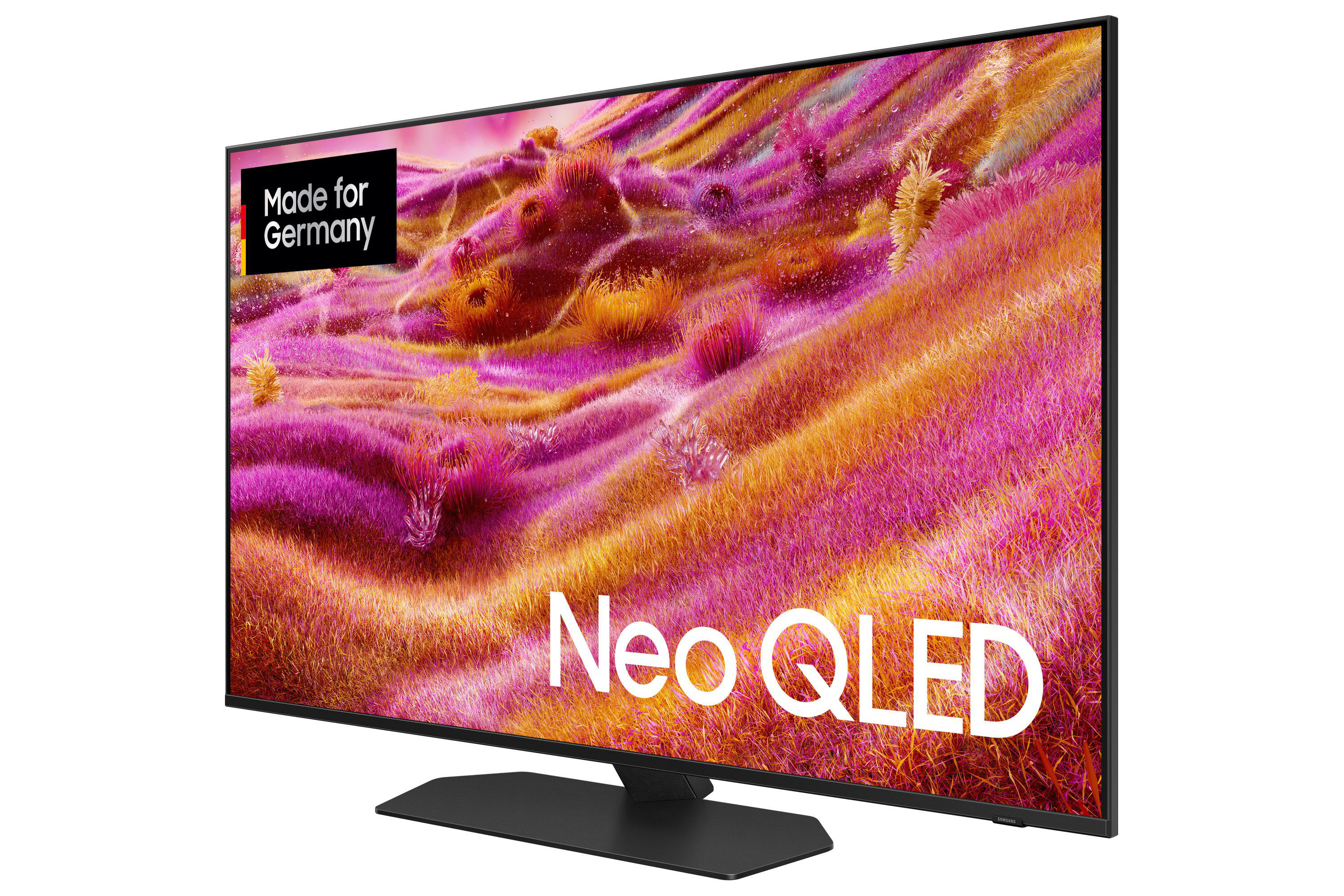 Ein Samsung Neo QLED-Fernseher zeigt ein farbenfrohes Feld. Es hat einen schwarzen Rahmen und Ständer. Der Bildschirm zeigt 'Neo QLED'.