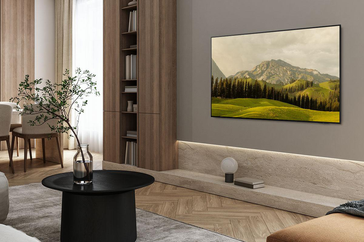Ein modernes Wohnzimmer mit Fernseher, der eine Landschaft zeigt. Es gibt einen Couchtisch mit Pflanze, Holzschrank und beigem Sofa.