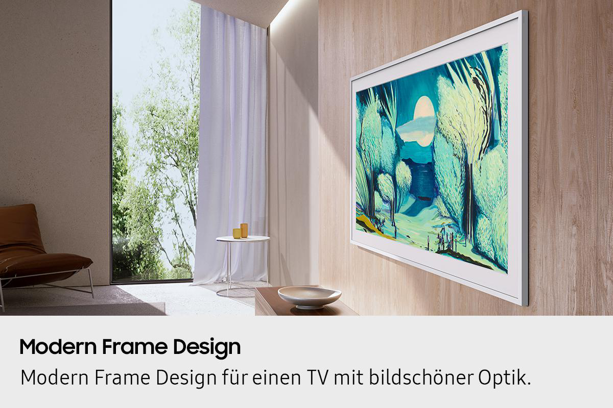 Ein modernes Wohnzimmer mit einem gerahmten Fernseher, der Kunst zeigt. Ein Stuhl, Tisch und Fenster mit Blick auf Bäume sind zu sehen.