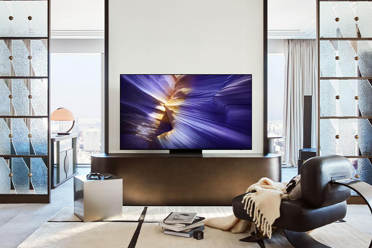 Wohnzimmer mit großem Fernseher, abstrakte Kunst auf dem Bildschirm. Mit Sessel, Teppich, Beistelltisch und Stadtblick.