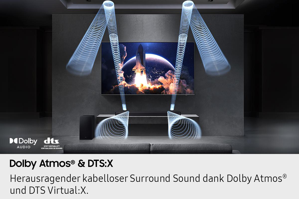 Ein modernes Wohnzimmer mit einem Fernseher, der einen Raketenstart zeigt. Schallwellen gehen von einer Soundbar aus, mit Subwoofer und Dolby Atmos Logo.