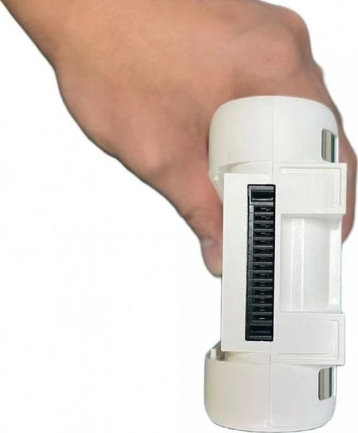 Ręka trzyma białe urządzenie z czarnym otworem wentylacyjnym. Urządzenie jest cylindryczne z prostokątnymi sekcjami.