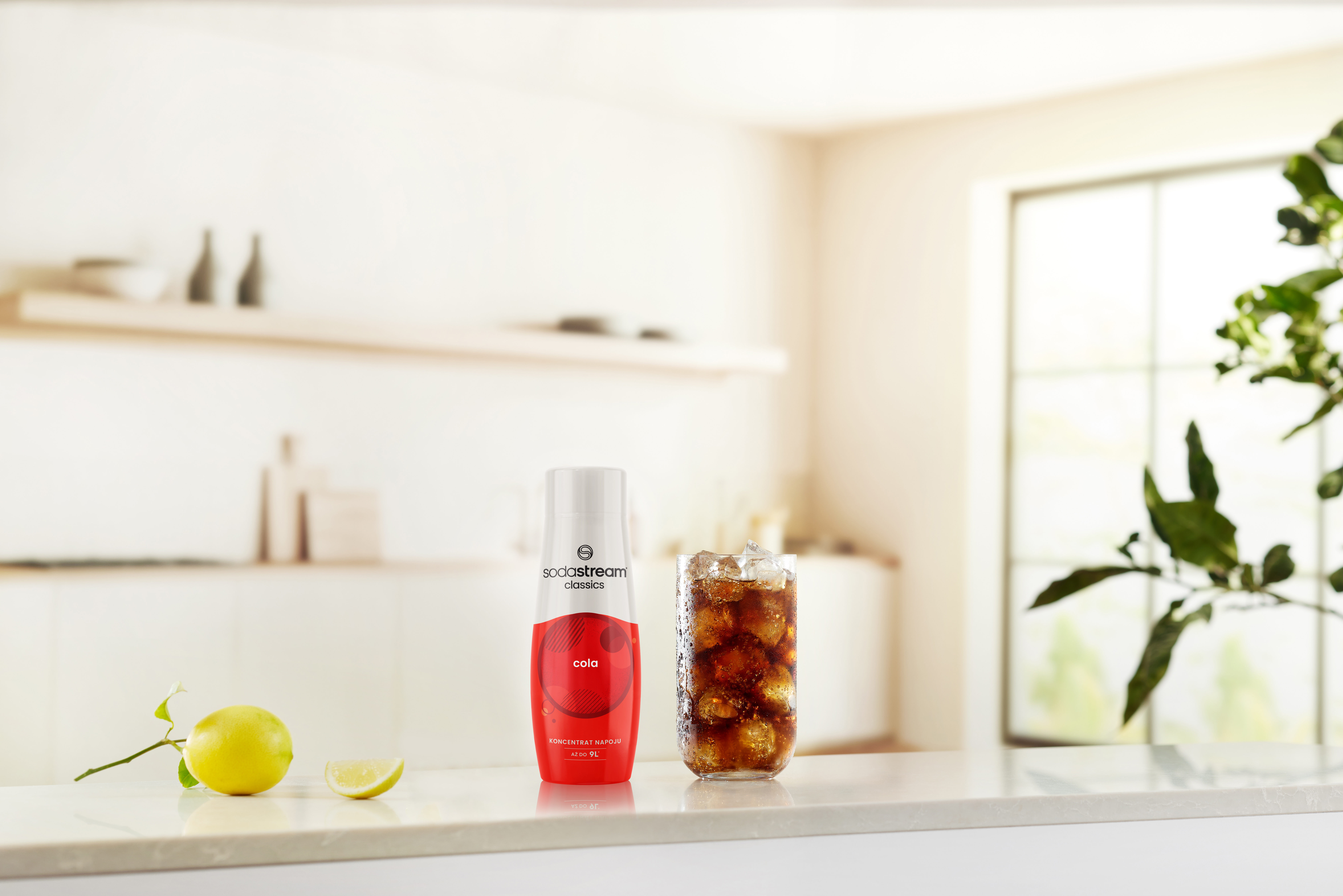 Napój coli z lodem, koncentratem coli SodaStream i cytryną na blacie. Tło kuchni.