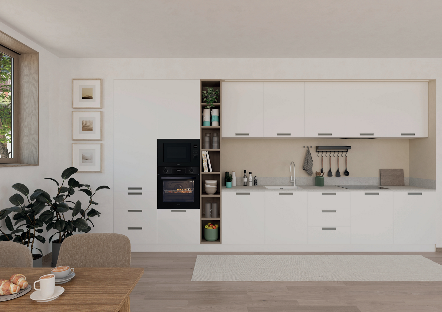 Cocina moderna con armarios blancos, horno empotrado y mesa de madera para desayunar. Hay una ventana y plantas.