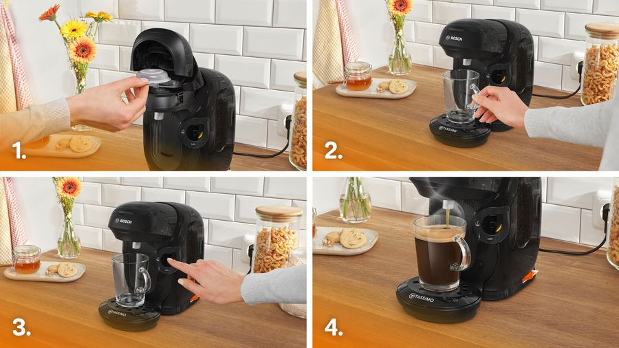 Una cafetera negra con una taza de vidrio. Una persona está haciendo café. Flores y aperitivos al lado.
