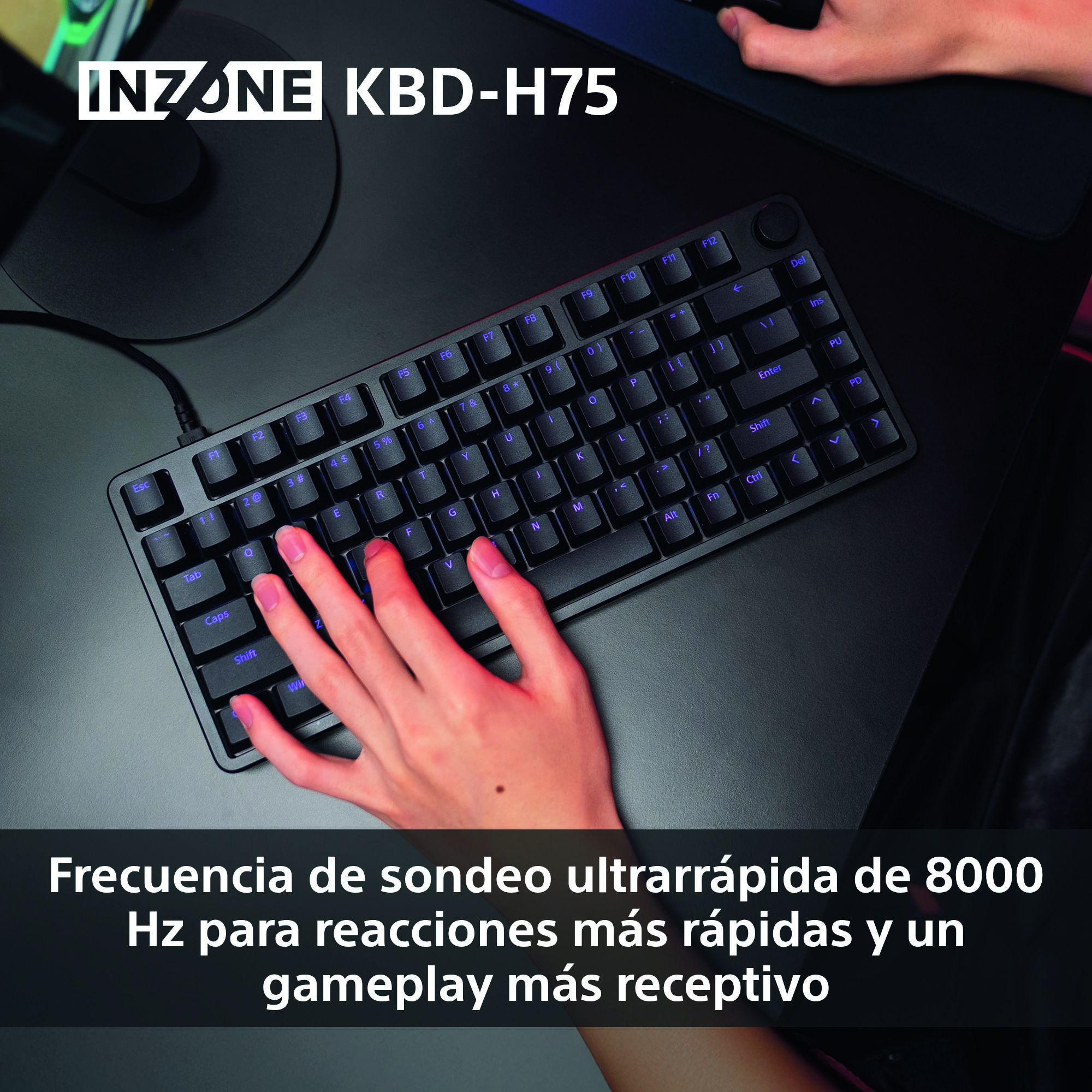 Un teclado negro está en un escritorio negro. Una mano descansa sobre el teclado. Las teclas se iluminan con un brillo púrpura.