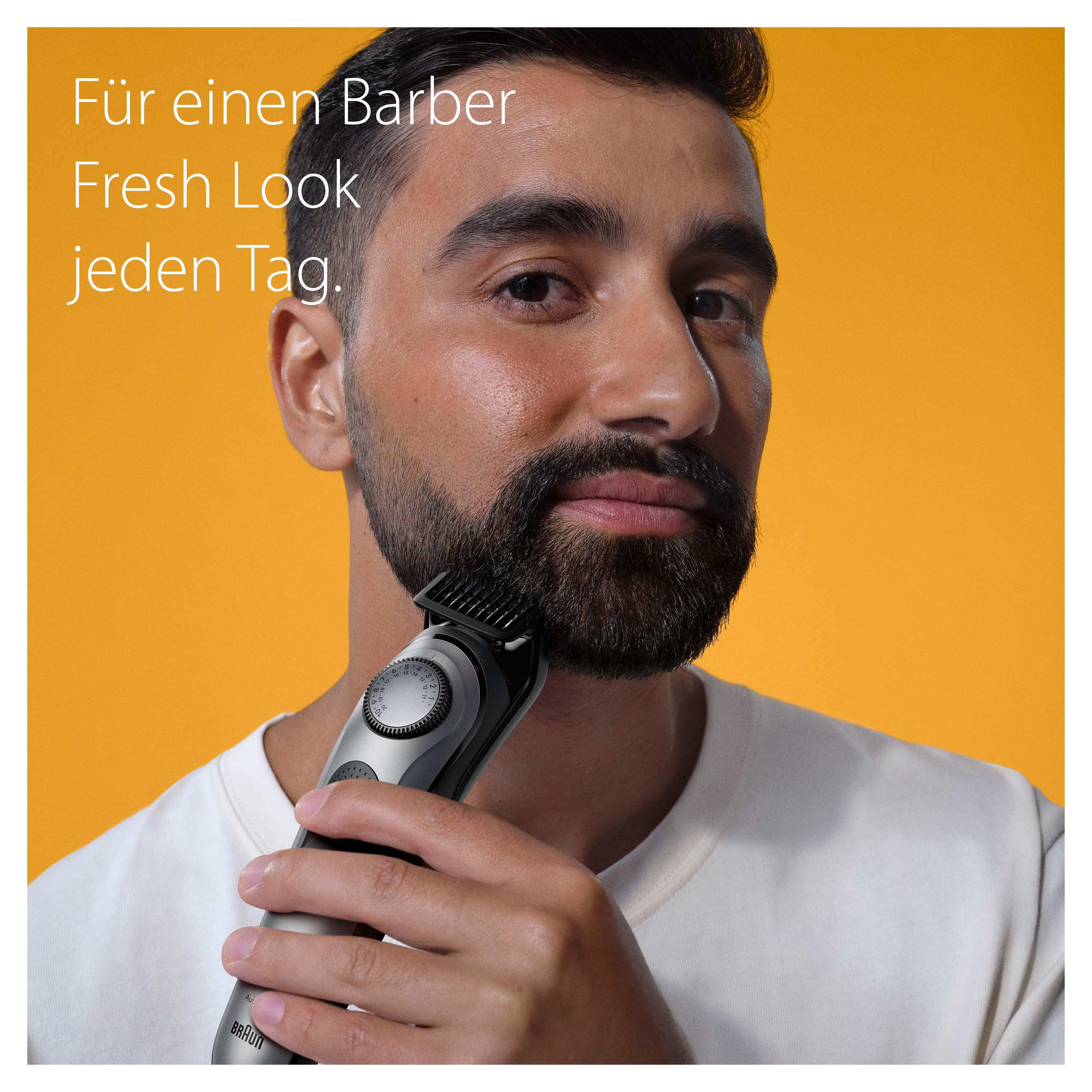 Ein Mann rasiert seinen Bart mit einem elektrischen Trimmer. Der Hintergrund ist orange.