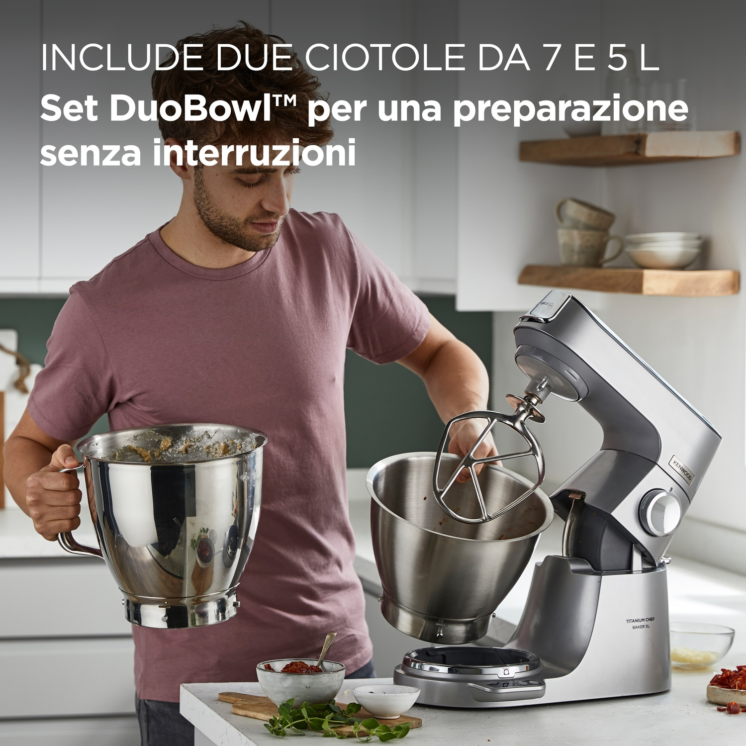 Un uomo in cucina tiene una ciotola, usando un mixer. Ingredienti e mixer sul bancone. Include testo sul set DuoBowl.