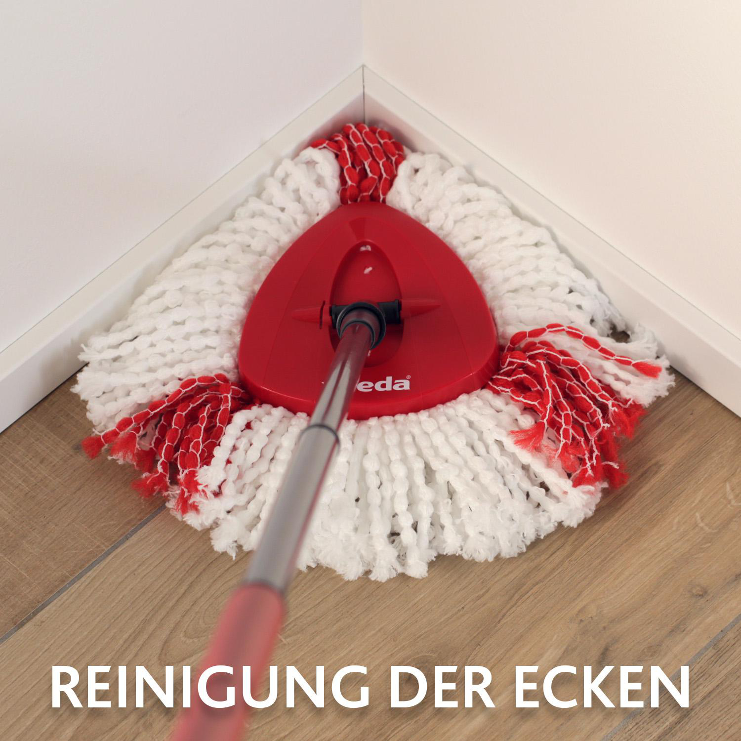Ein roter und weißer Wischmopp befindet sich in einer Ecke. Der Wischmoppkopf ist dreieckig und liegt auf einem Holzboden. Der Text lautet 'Reinigung der Ecken'.