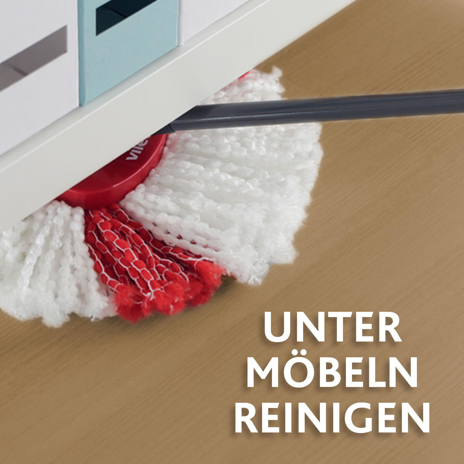 Ein weißer und roter Wischmopp, der unter Möbeln reinigt. Der Text "UNTER MÖBELN REINIGEN" befindet sich auf dem Boden. Im Hintergrund ein Holztisch.