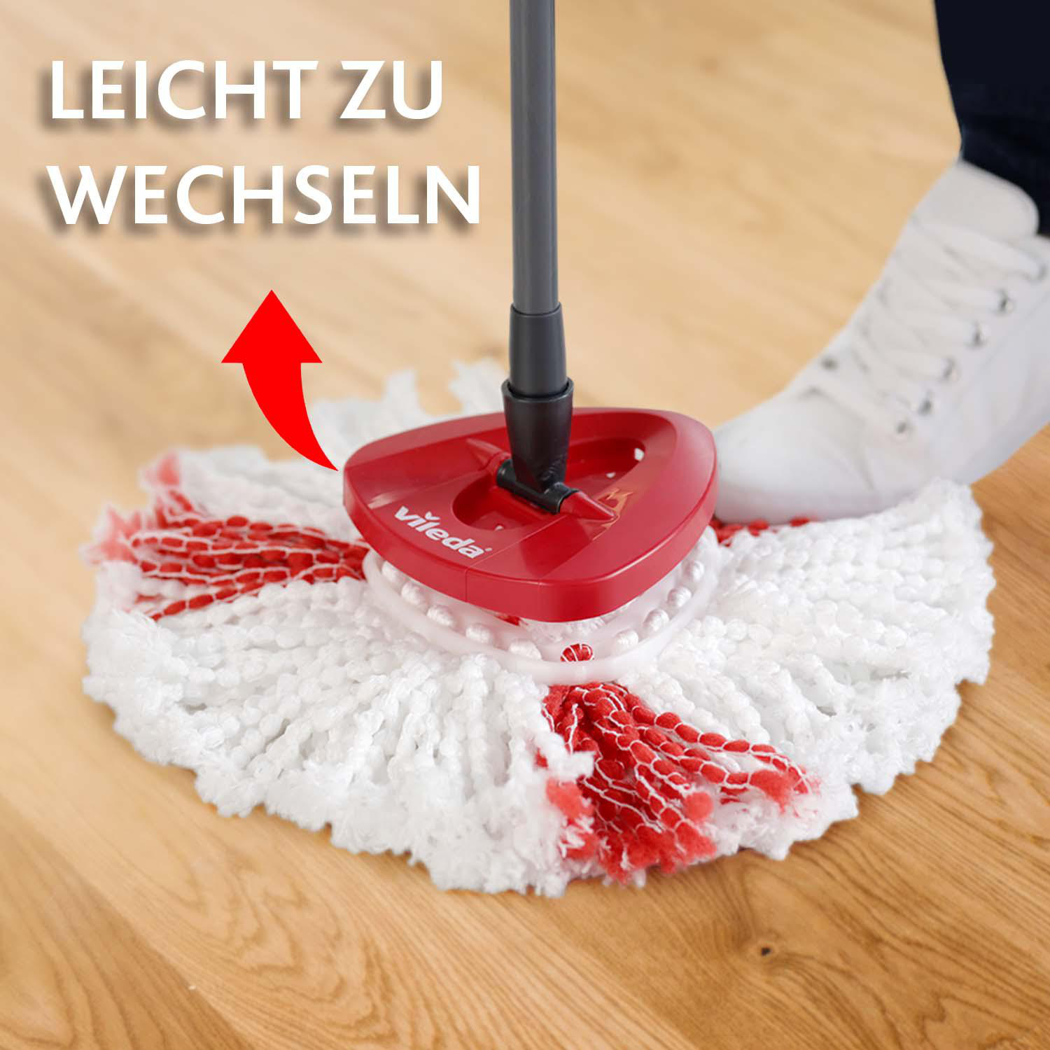 Ein rot-weißer Vileda-Moppkopf auf einem Holzboden. Die Worte 'LEICHT ZU WECHSELN' und ein Pfeil sind im Hintergrund.