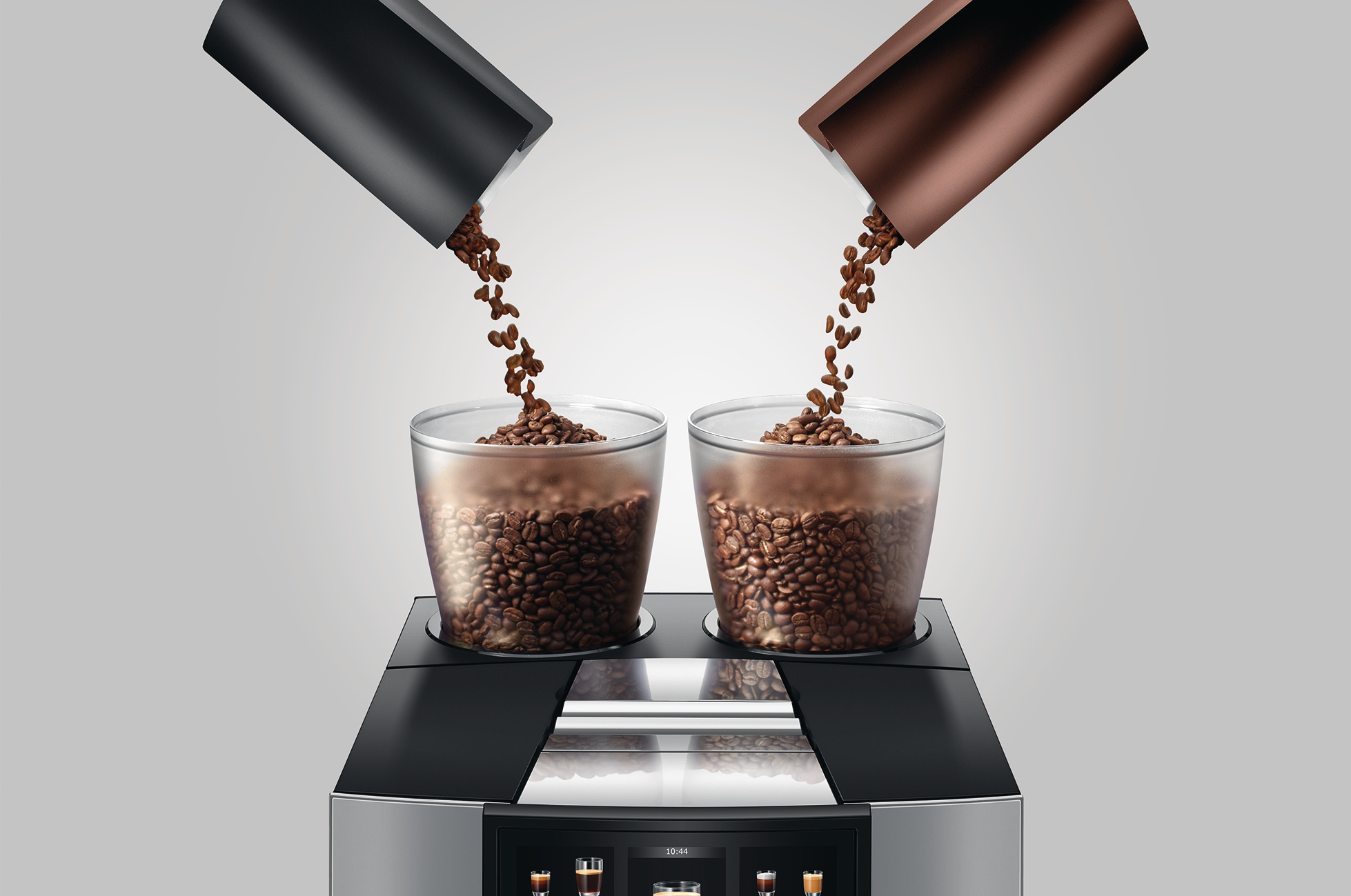 Zwei Behälter gießen Kaffeebohnen in Gläser auf einer Kaffeemaschine. Der Hintergrund ist ein Weiß-Grau-Verlauf.