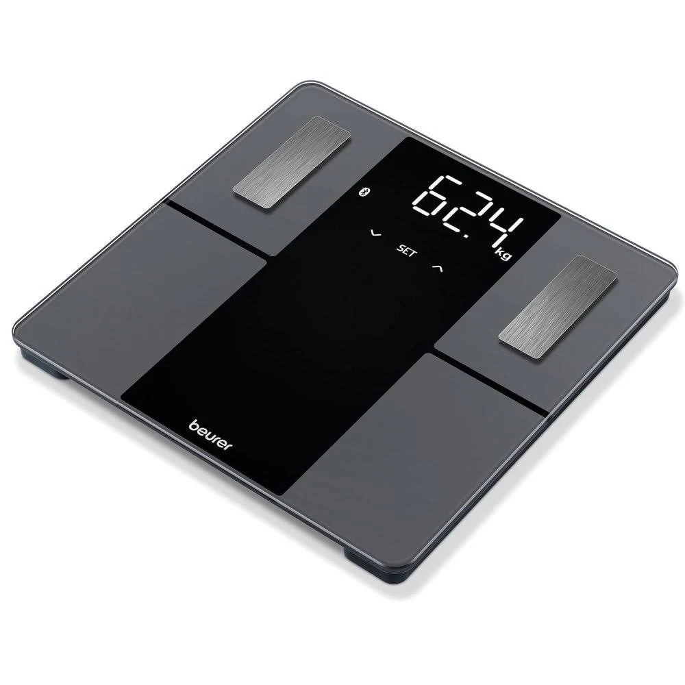 Una báscula de baño digital, mostrando 62,4 kg. Es gris oscuro con un panel central negro y detalles metálicos plateados.
