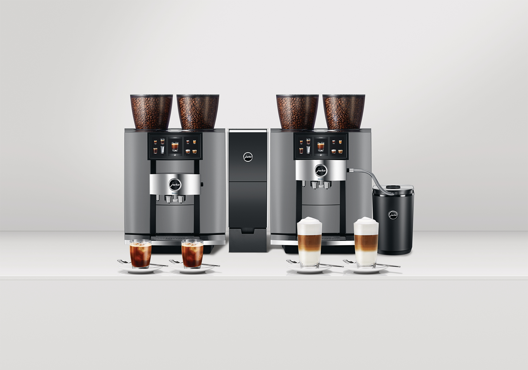 Zwei Kaffeemaschinen mit Kaffeebohnen, Kaffeegetränken und Milchschaum werden auf einer weißen Oberfläche präsentiert. Der Hintergrund ist weiß.