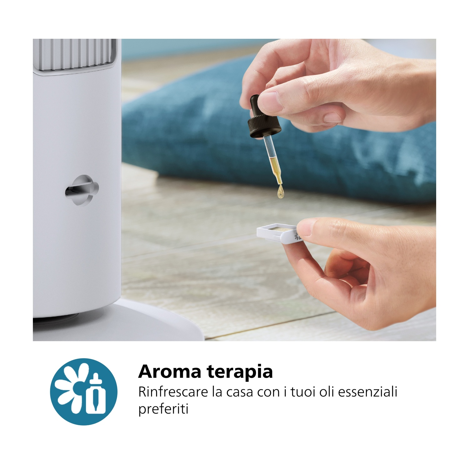 Mani che tengono un contagocce di olio essenziale sopra un vassoio bianco e un purificatore d'aria. Un cuscino blu sullo sfondo. Testo: Aromaterapia.