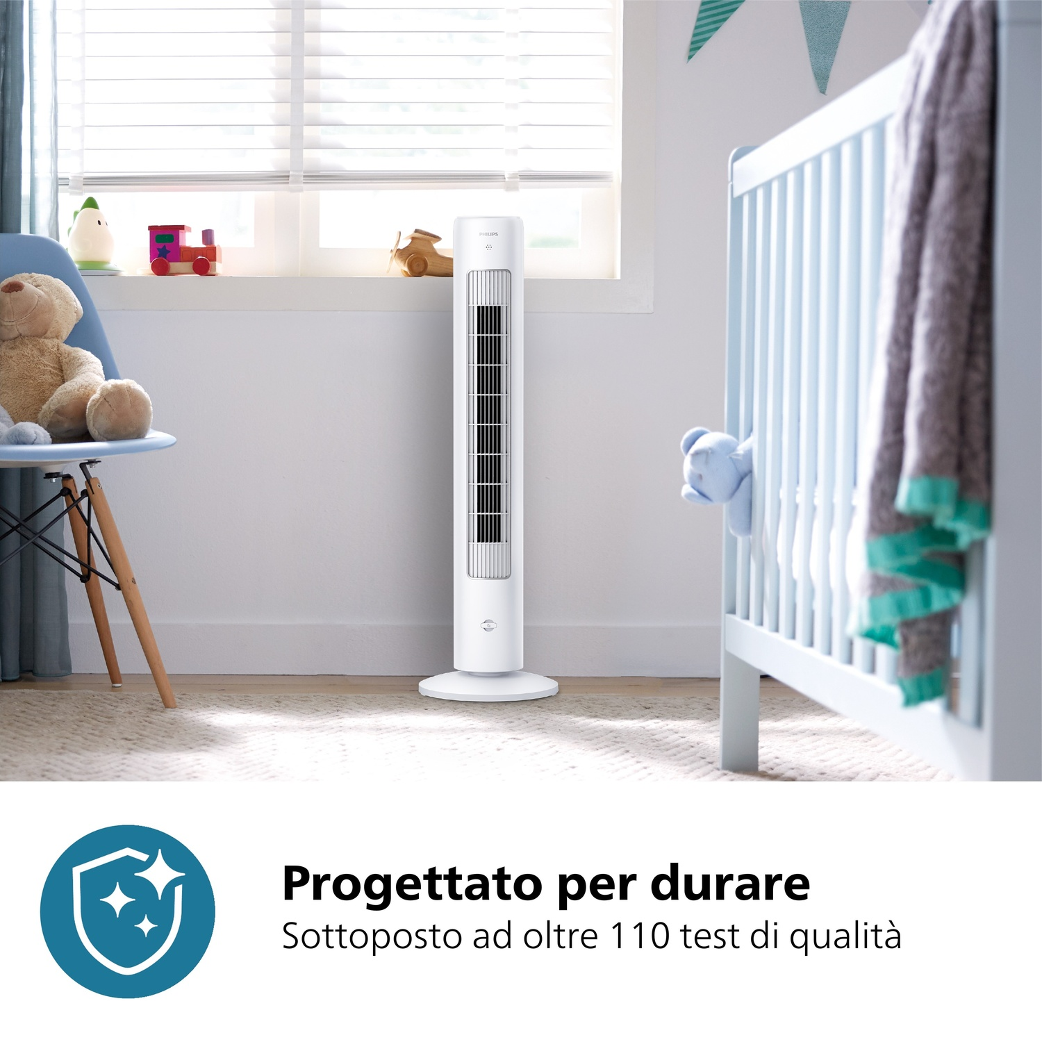 Un ventilatore bianco è in una cameretta. Un lettino blu, un orsacchiotto e giocattoli sono visibili. Le persiane coprono la finestra.