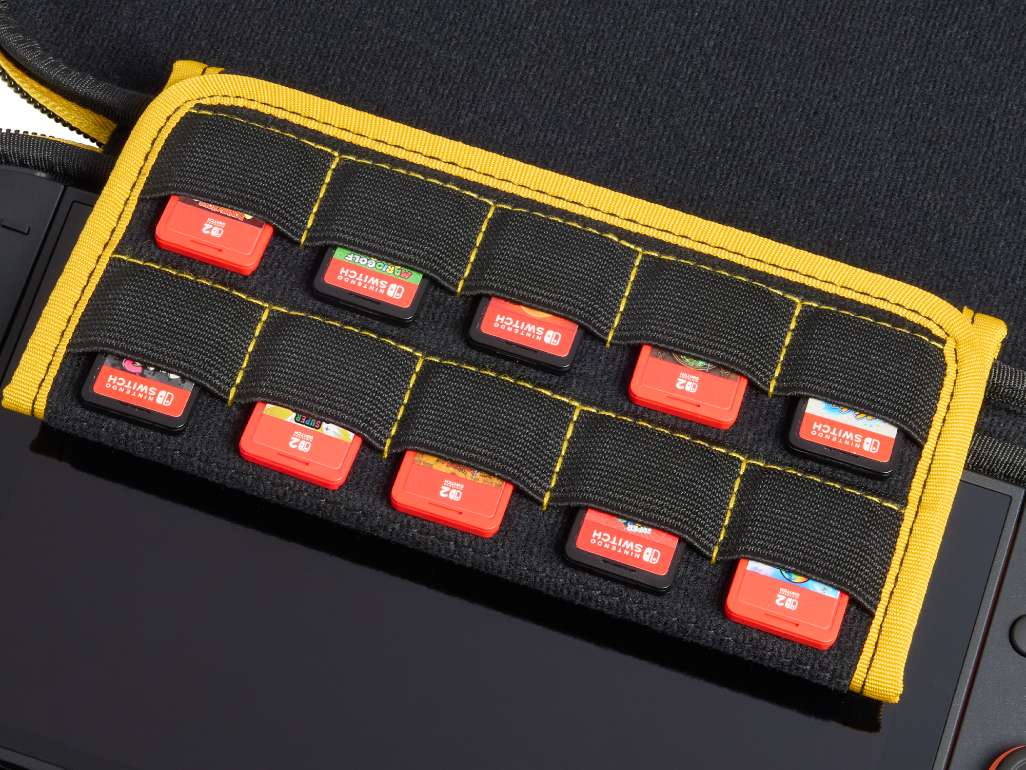 Ein schwarzes Etui mit gelbem Rand enthält Nintendo Switch-Spielekassetten. Rote Spielkarten sind sichtbar, teilweise in das Etui gesteckt.