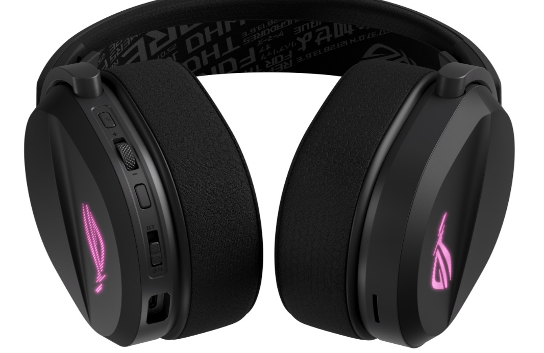 Cuffie da gioco nere con padiglioni e fascia imbottiti. Il padiglione destro ha un controllo del volume e un logo rosa brillante.