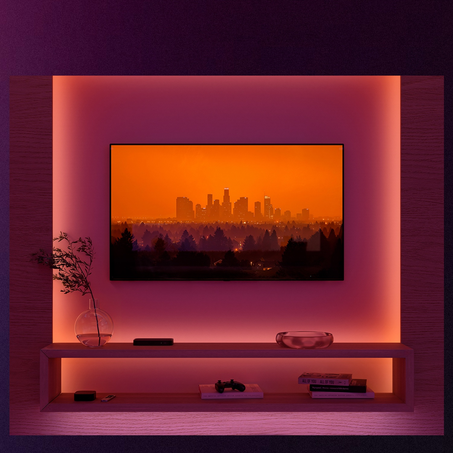TV met skyline bij zonsondergang. Een plank eronder met spullen. De muur heeft sfeerverlichting.