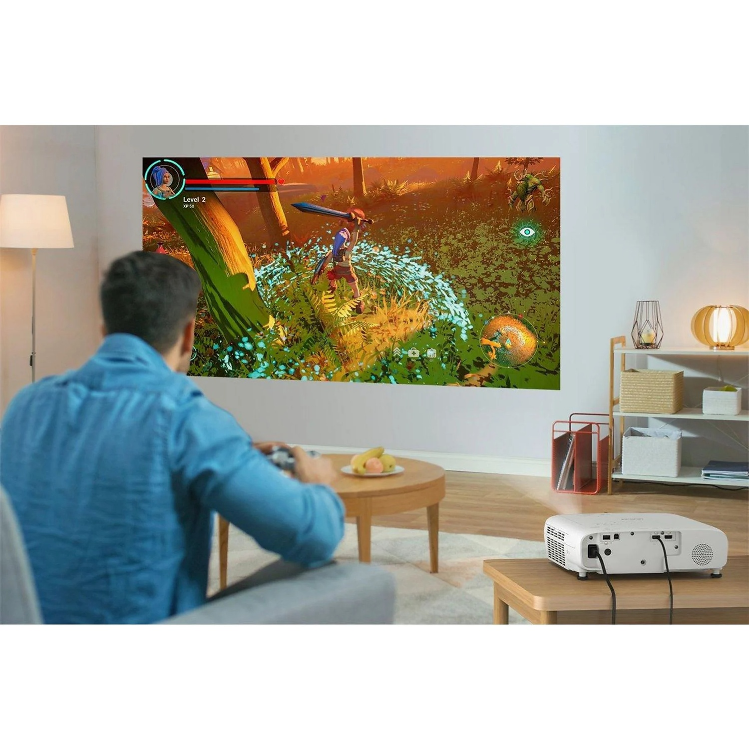 Man speelt een videogame die op een muur wordt geprojecteerd. De game toont een personage in een bos. Een projector staat op een tafel.