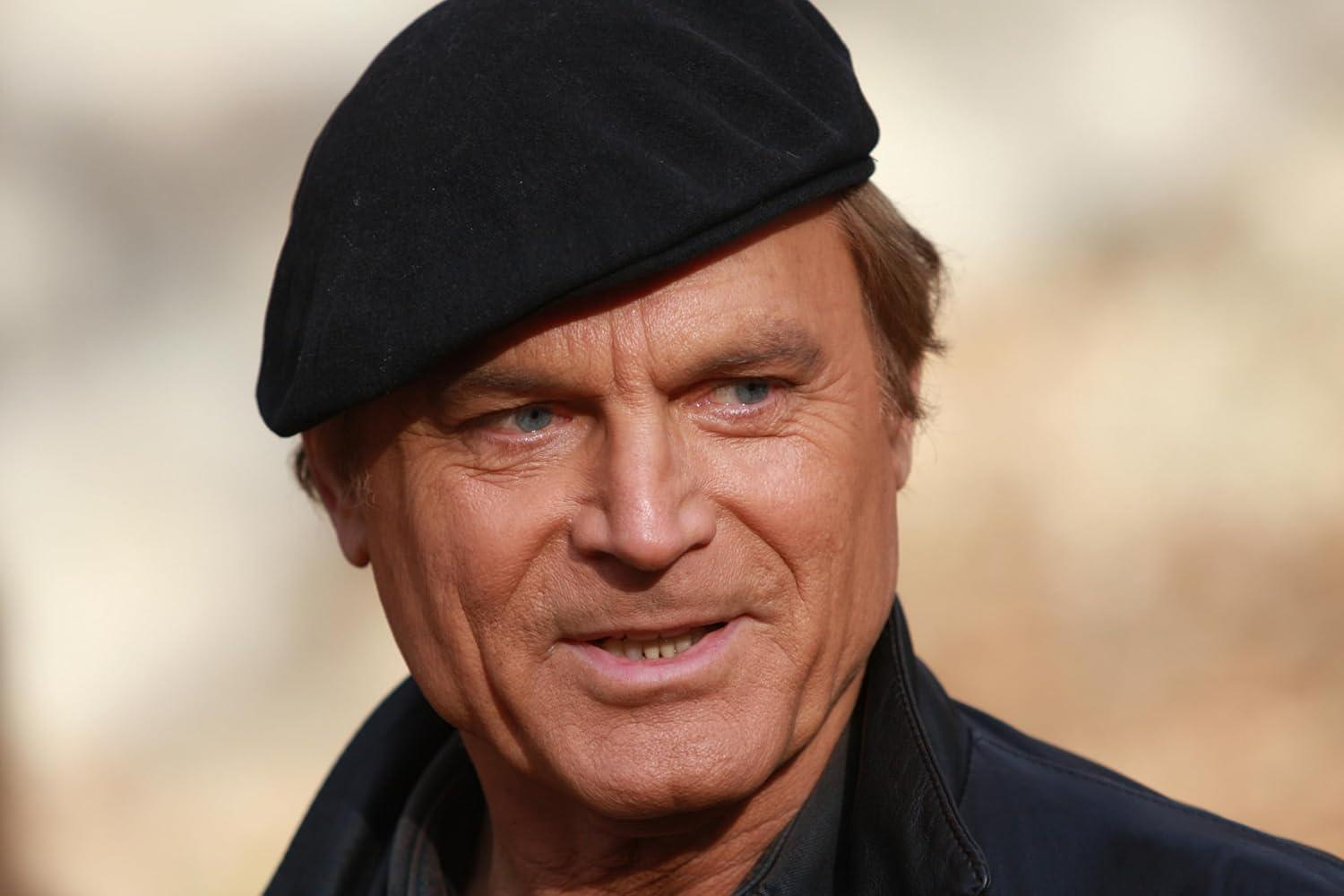 Mann mit blauen Augen und schwarzer Baskenmütze lächelt. Er trägt eine dunkle Jacke. Der Hintergrund ist verschwommen.