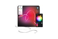 Un kit de bande lumineuse Philips Hue Flux avec un smartphone affichant des options de couleur et une boîte avec les détails du produit. La lumière est blanche.