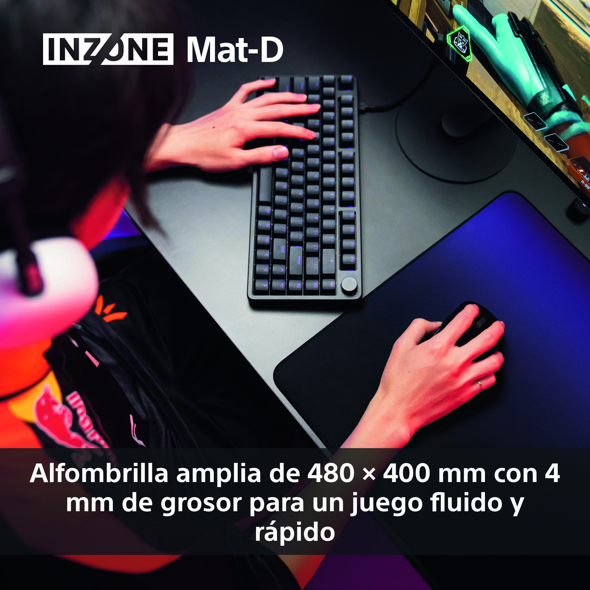 Una persona usa un teclado y un ratón negros en un escritorio. Se ve una alfombrilla de ratón para juegos, un teclado y un monitor.