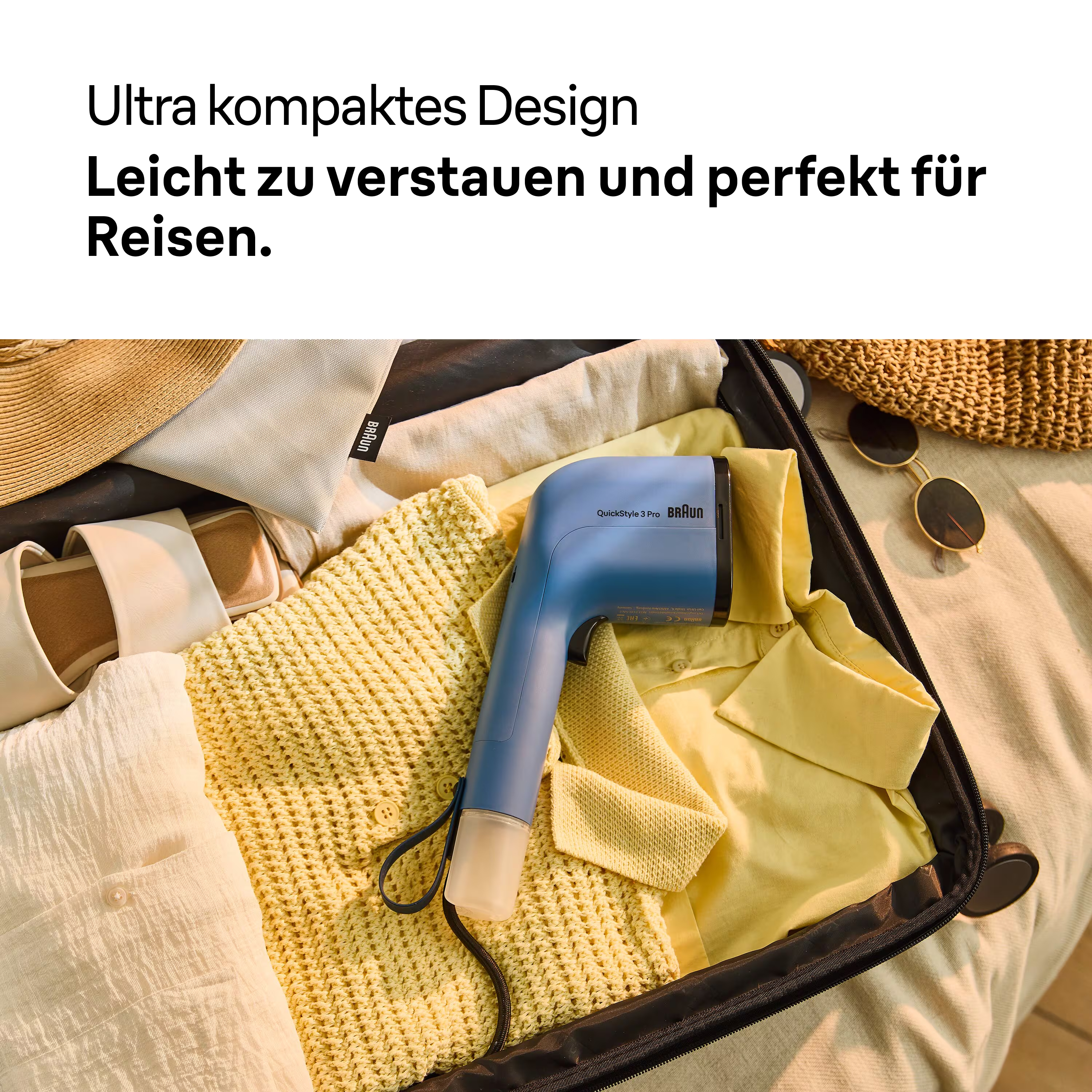 Ein blauer Braun-Dampfer liegt in einem offenen Koffer, der mit Kleidung, einem Hut und einer Sonnenbrille gefüllt ist. Der Dampfer ist mit QuickStyle 3 Pro beschriftet.