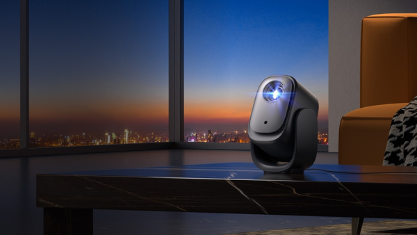 Czarny projektor na stole, przed panoramą miasta o zmierzchu. W tle kanapa. Projektor jest włączony.