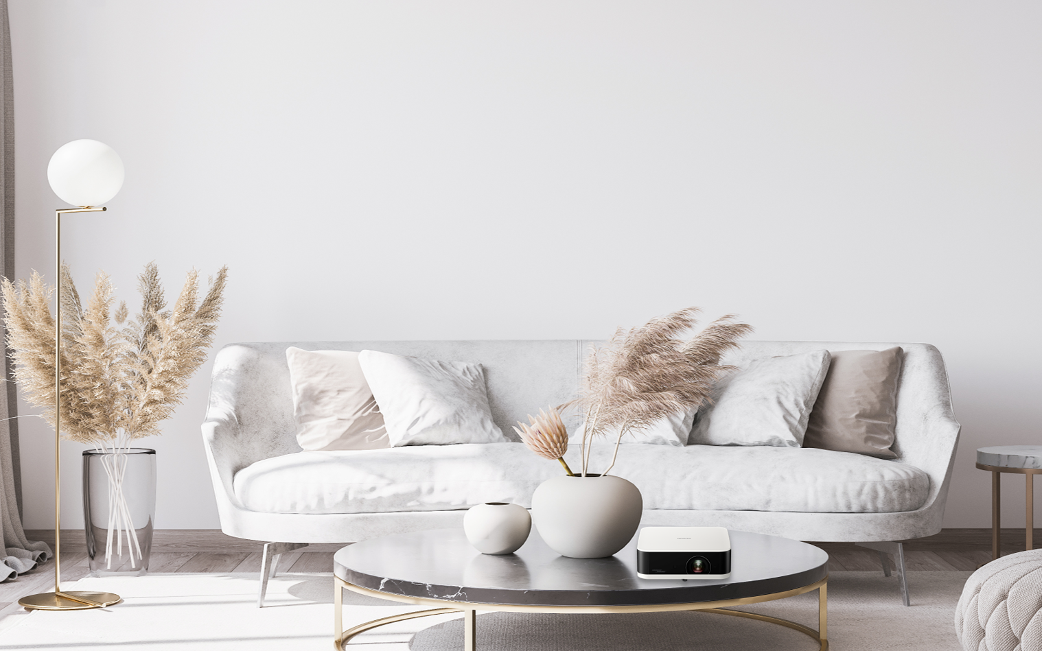 Wohnzimmer mit weißem Sofa, rundem Tisch, Vase mit Pampasgras und einem Projektor.