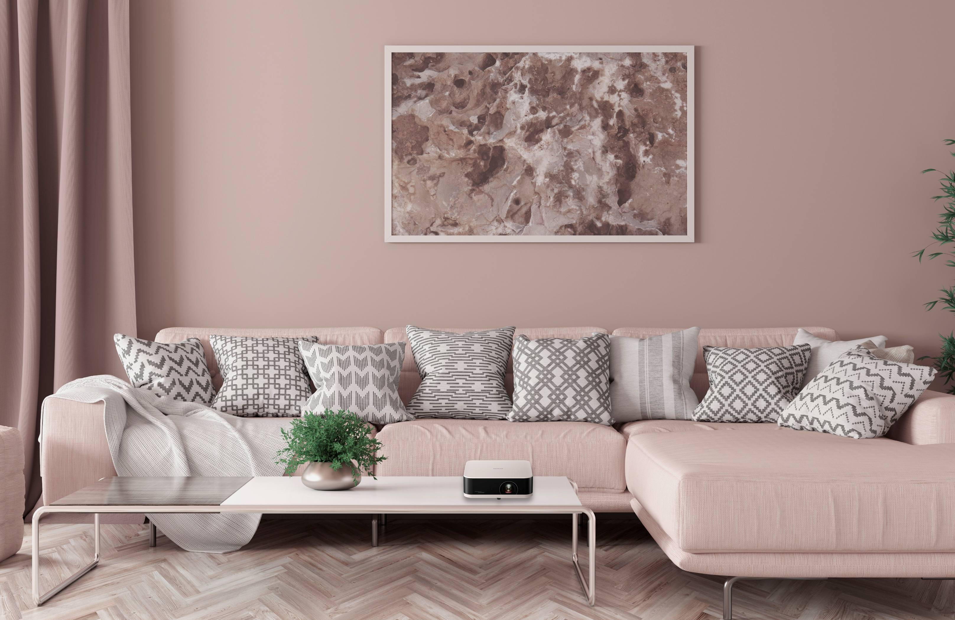 Un salon rose avec un canapé, des coussins, une table basse et un tableau encadré.