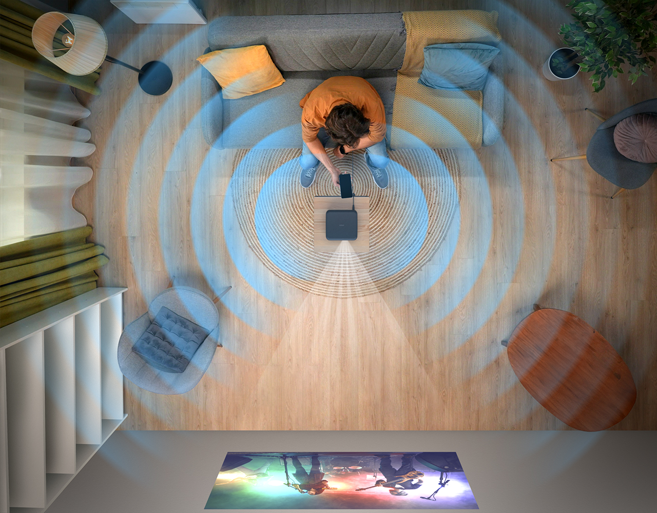 Eine Person sitzt auf einem Sofa und benutzt ein Telefon, ein Gerät auf einem Teppich. Blaue Wellen gehen aus. Ein Bildschirm zeigt eine Band.