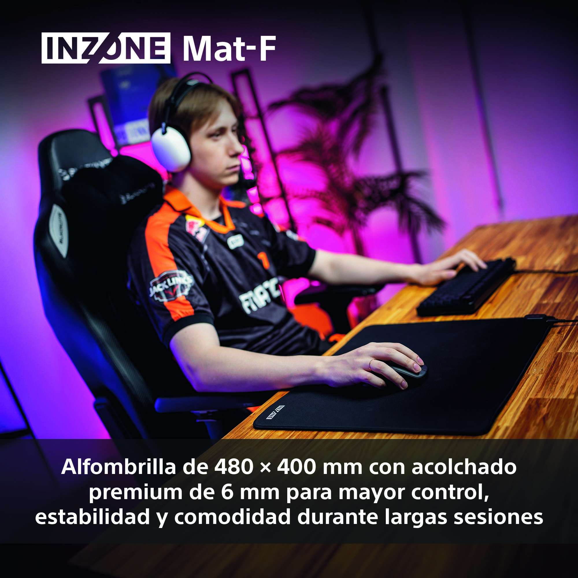 Una persona con auriculares usa un ratón y un teclado sobre una alfombrilla negra. La escena está preparada para jugar.
