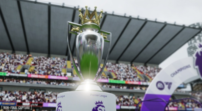 Premier League-Trophäe auf einem Sockel vor einem Stadion mit Fans. Die Trophäe ist silber und gold, mit einer Krone oben.