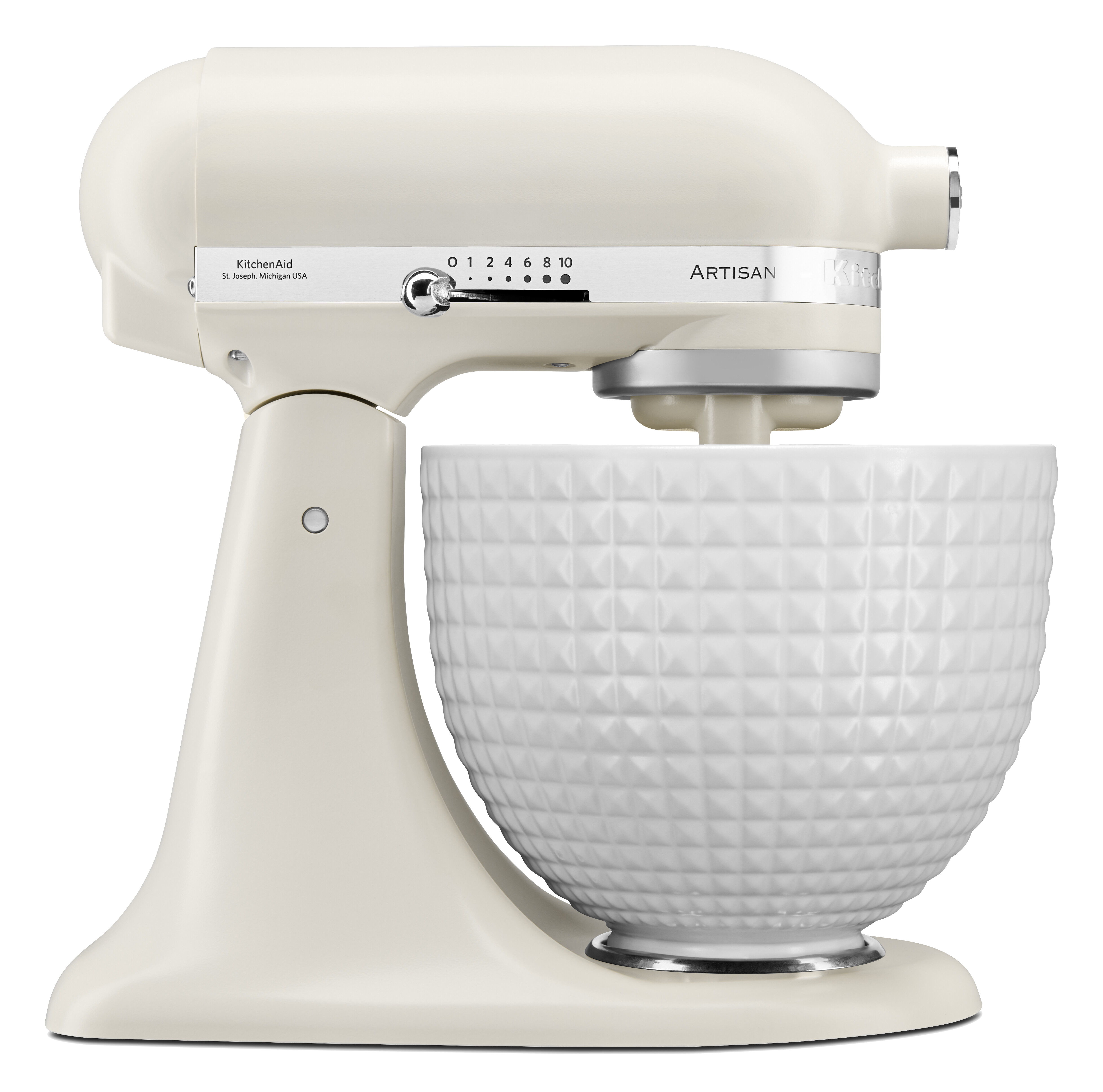 Ein cremefarbener KitchenAid Artisan Standmixer mit einer weißen Schüssel mit Rautenmuster, vor schwarzem Hintergrund.