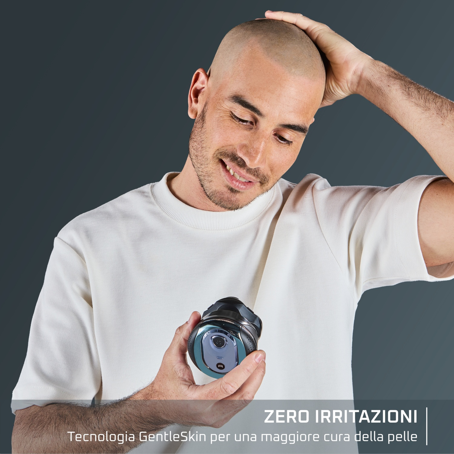 Un uomo calvo guarda un rasoio nelle sue mani. Indossa una camicia bianca. Lo sfondo è grigio scuro e uniforme.