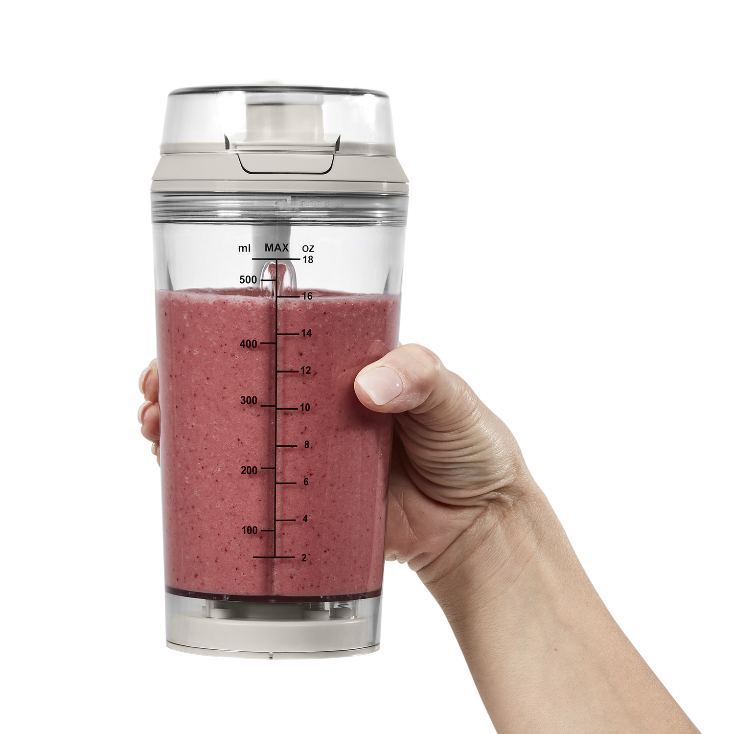 A hand holds a blender bottle filled with pink smoothie. The bottle is clear, with measurements. The background is black.